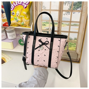 Détail du sac rose à texture bulle avec nœud noir et pendentif cœur à la main