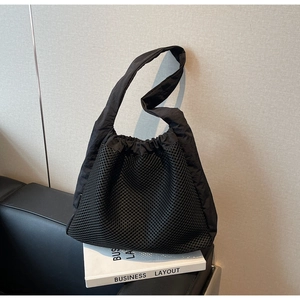Detail of minimalist black nylon mesh tote bag with functional drawstring closure and texture