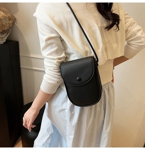 Détail d'un petit sac bandoulière en cuir noir grainé porté par un mannequin