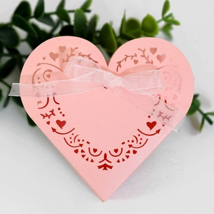 Macro view of heart-shaped pink favor box with laser-cut patterns and soft silk ribbon