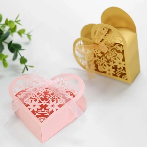 Detail of laser-cut heart candy boxes with intricate flower patterns and silk ribbons