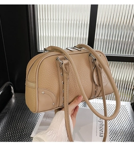 Detail of beige litchi grain leather Boston bag with silver hardware and dual handles