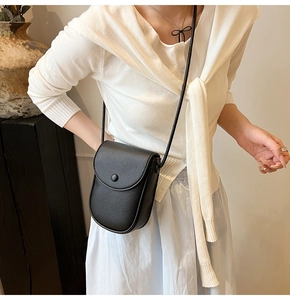Détail du sac de téléphone en cuir noir à motif litchi avec rabat à bouton rond