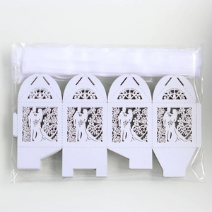 Macro detail of laser-cut wedding favor boxes with Mr & Mrs silhouette and white ribbon