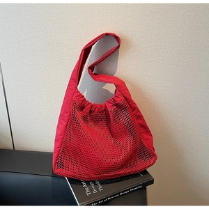 Detail of red hollow nylon tote bag with mesh texture and wide shoulder strap