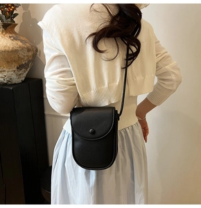Détail du sac à téléphone en cuir grainé noir porté par le mannequin pour la taille et texture