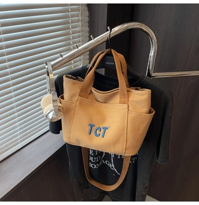 Détail du sac cabas en toile jaune avec broderie TCT bleue et bandoulière réglable