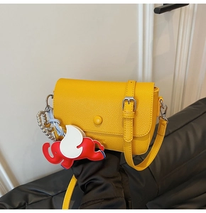 Close-up of yellow litchi pattern leather bag with flying elephant charm detail