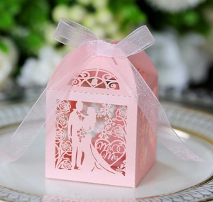 Detail of pink laser-cut wedding favor box with Mr & Mrs silhouette and organza ribbon