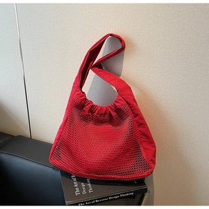Detailed close-up of a red mesh nylon tote bag placed on a black leather surface