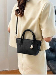 Sac seau élégant en cuir grainé noir avec pendentif coeur porté par un mannequin