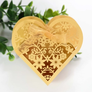 Close-up of golden hollow heart wedding favor box with floral laser cut and ribbon bow