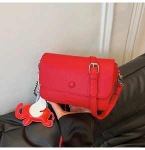 Close-up of red lychee pattern leather shoulder bag featuring a cute elephant charm