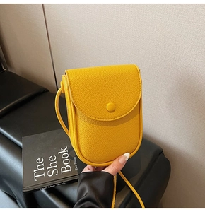 Détail d'un petit sac à bandoulière en cuir jaune grainé pour téléphone avec rabat chic