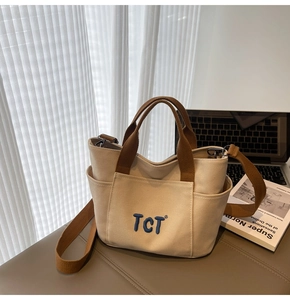 Détail du sac cabas en toile avec broderie TCT bleue et poches latérales sur cuir