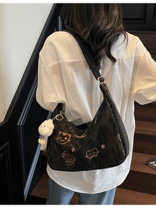 Black Hobo tote bag with cat print and white plush charm on dark wooden stairs