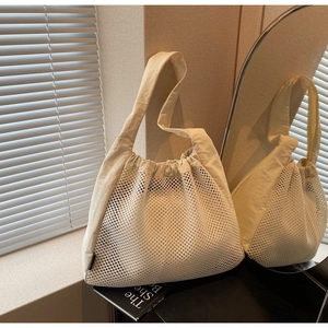 Detail of cream mesh tote bag with wide shoulder strap in a bright sunlit setting