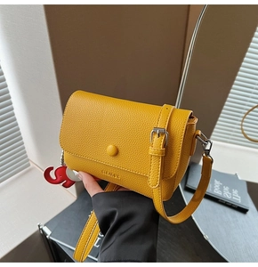 Detail of yellow lychee texture crossbody bag with silver buckle and red elephant charm