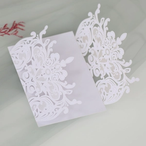 Macro detail of laser-cut lace floral pattern on elegant white wedding invitation card