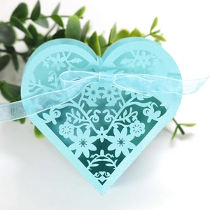 Detail of light blue heart-shaped favor box with intricate laser-cut floral patterns