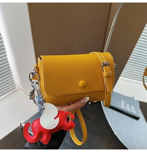 Close-up of yellow textured crossbody bag featuring a cute elephant charm accessory