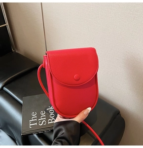 Détail du mini sac bandoulière rouge en cuir grainé avec un rabat semi-circulaire
