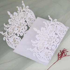 Intricate laser-cut white wedding invitation with elegant European floral patterns