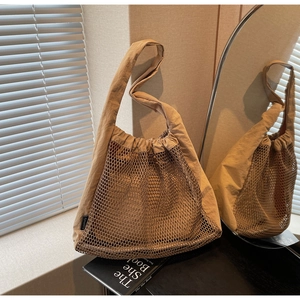 Detail view of large beige hollow-out nylon mesh tote with inner lining and mirror reflection
