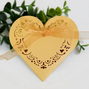 Detail showing golden laser-cut heart candy box with intricate floral patterns and ribbon