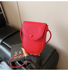 Détail du sac de téléphone rouge en cuir grainé avec fermoir décoratif magnétique