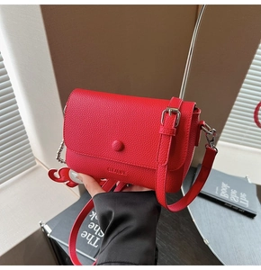 Macro view of red litchi texture leather crossbody bag with circular CLEARCK buckle