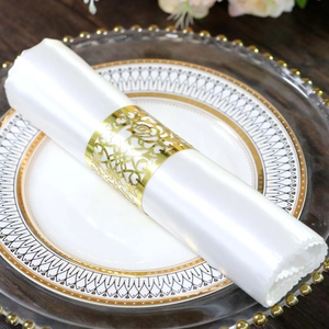 Close-up of golden hollow rose napkin ring on a white silk napkin for elegant dining setup