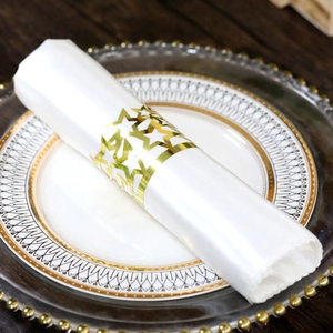Detail of laser-cut gold star napkin ring with hollow design on a white dinner napkin