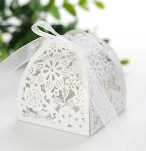Detailed laser-cut hollow floral pattern on a white wedding favor box with ribbon bow