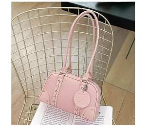 Close-up of pink lychee grain leather bag with metal rivets on a gold mesh chair