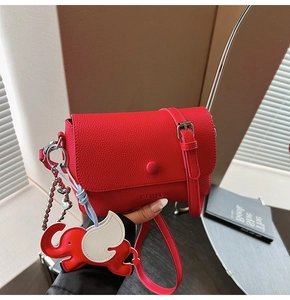 Close-up of red lychee leather texture with adjustable strap and elephant charm