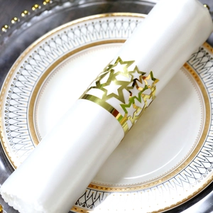 Detail of a gold star napkin ring with cutout design on a white linen napkin