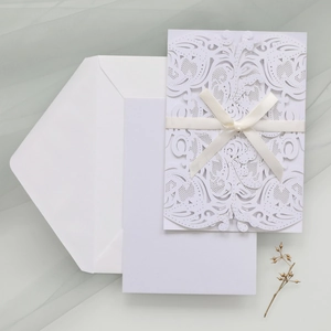 Lace laser-cut wedding invitation set with cream ribbon and white envelope detail