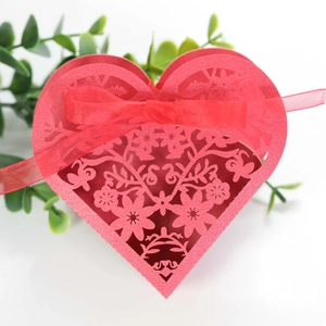 Macro shot of red heart laser-cut candy box with intricate floral hollow pattern and ribbon