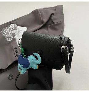 Close-up of black litchi grain leather crossbody bag with silver buckle and elephant charm