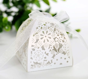 Close-up of laser-cut floral pattern on white gift box with white organza ribbon bow