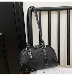 Detailed view of black pebbled leather pillow bag with silver zippers and rivet details