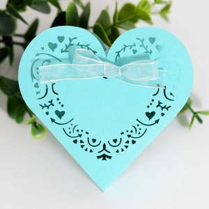 Detail of light blue heart-shaped laser cut wedding favor box with a satin bow