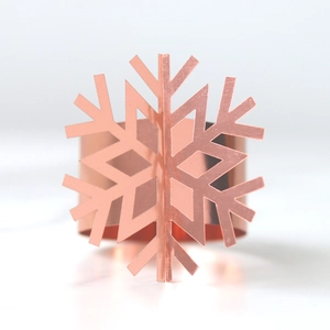 Detailed view of rose gold laser-cut snowflake napkin ring with polished metallic finish