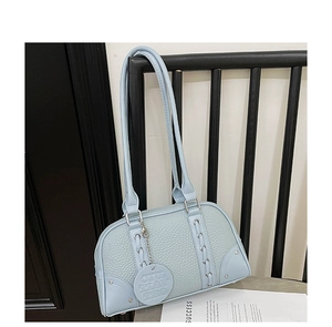 Light blue lychee pattern shoulder bag with silver hardware on a chair backrest