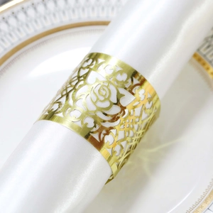 Detail of gold hollow rose napkin ring on a white satin napkin for wedding decor
