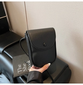 Détail du mini sac de téléphone en cuir noir à motif litchi avec rabat arrondi