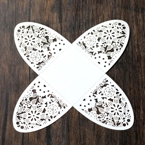 Detailed laser-cut floral pattern on unfolded white paper wedding gift box template