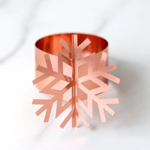 Close-up of rose gold snowflake napkin ring on marble background for table decor