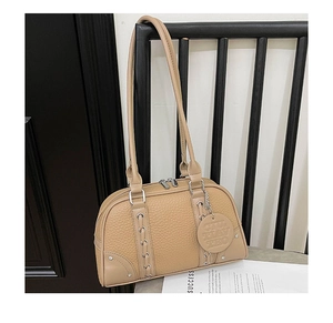 Close-up of beige lychee texture leather shoulder bag with metal weave detail and strap